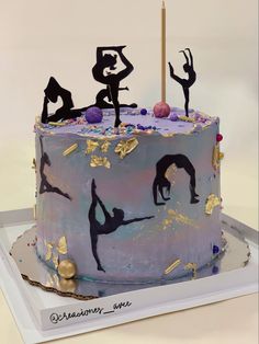 there is a cake that has three people on it and two candles in the shape of dancers