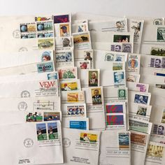 many mail envelopes are stacked on top of each other with stamps attached to them