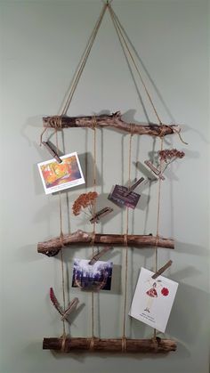 a wooden shelf with pictures hanging from it's sides and some rope attached to the wall