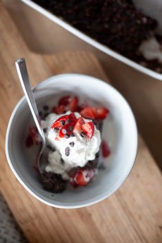 a bowl filled with ice cream and strawberries on top of a wooden cutting board