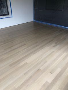 an empty room with hard wood flooring and blue tape on the wall behind it