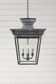 an outdoor hanging light with three candles on the bottom and one candle in the middle