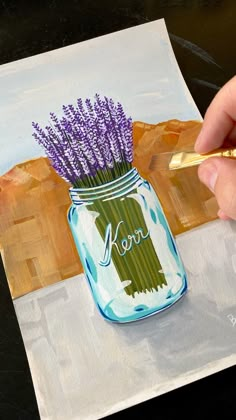 a painting of a mason jar with lavenders in it is being painted by someone's hand