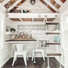 a small room with white chairs and wooden walls, along with a ladder leading up to the loft