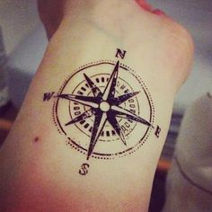 a black and white compass tattoo on the arm