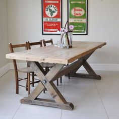 a wooden table with four chairs in front of two posters on the wall above it