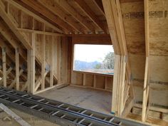 an unfinished room with wooden framing and windows