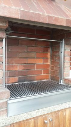 an outdoor bbq grill with brick walls and steel grates on the bottom shelf