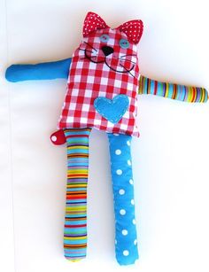 a colorful stuffed animal laying on top of a white surface with polka dots and hearts