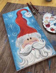 a painting of a santa clause on a canvas next to paintbrushes and watercolors