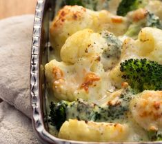 a casserole dish with broccoli and cauliflower in it on a towel