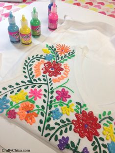 a table topped with lots of crafting supplies and flowers on top of white paper