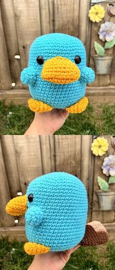 a hand holding a crocheted blue bird in front of a wooden fence with flowers