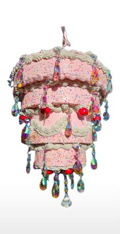 a pink cake with sprinkles hanging from it's side on a white background