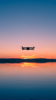 a small plane flying over the water at sunset