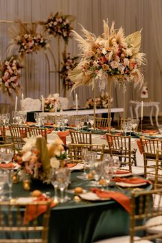 the tables are set with gold chairs and tall centerpieces for an elegant reception