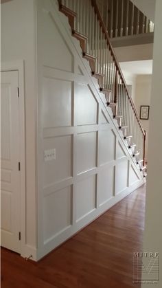 an empty room with wooden floors and white doors on the side of the wall, next to a stair case