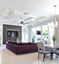 a living room filled with furniture and a flat screen tv mounted to the wall next to a dining table