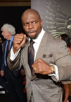 a man in a suit and tie pointing at the camera with other people behind him