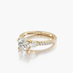 a yellow gold engagement ring with an oval cut diamond on the side and pave set shoulders