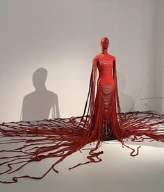 a woman is standing in the middle of a room with red yarn on the floor