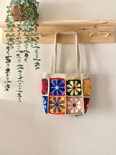 a white bag hanging on a wall next to a wooden rack with plants in it