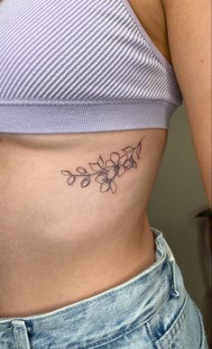 a woman's stomach with a flower tattoo on the side of her belly,