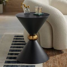 a black table with gold accents on it in front of a white chair and rug