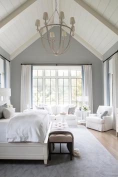 a bedroom with white furniture and large windows