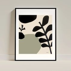 a black and white framed art print with leaves on the bottom, in front of a wall