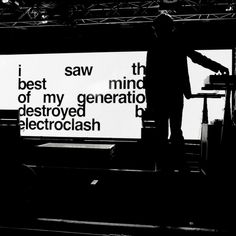 a man standing on top of a stage next to a large sign that says i saw the best of my generation destroyed electroclash