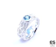 This ring is made of 925 sterling silver.  It has a beautiful, resistent and irregular surface on the outside.  This ring has a natural 5,0 mm Sky Blue Topaz gemstone set in. The inside of the ring is polished and domed in order to achieve a very smooth and comfortable fit on your finger. Remember that every ring is handmade and always one of a kind. Ring is about 8 mm wide and weighs at least 10 grams. Available from ring size: 48 (4 1/2 US) to 65 (11 1/2 US) All ES Jewelry products are shipped Modern Topaz Ring For Promise, Modern Blue Topaz Promise Ring, Modern Silver Blue Topaz Ring, Modern Blue Topaz Ring, Sky Blue Topaz Ring, Blue Gemstone Ring, Blue Gemstone Rings, Jewellery Designer, Sky Blue Topaz