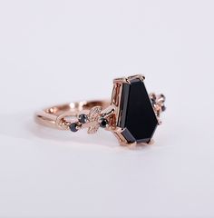 a close up of a black stone ring on a white surface with gold trimmings