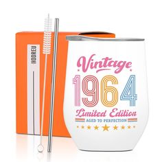 an orange and white tumbler with a straw in it next to a boxed box