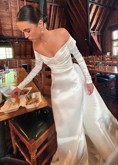 a woman in a white dress is cutting food