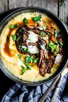 a bowl filled with mashed potatoes topped with meat and garnished with parsley