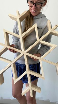 a young woman is holding a wooden snowflake that she made out of pieces of wood