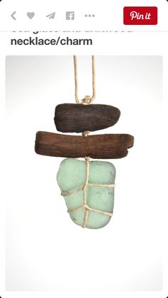 a piece of driftwood and sea glass hanging from a rope on a white background