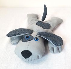 a stuffed dog laying on top of a white bed with blue eyes and nose covering