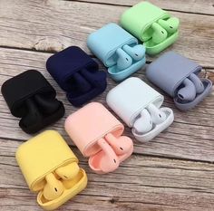 four different colors of ear buds sitting on top of a wooden table next to each other