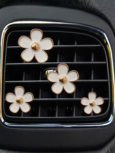 four white flowers are attached to the center console of a car's air vent