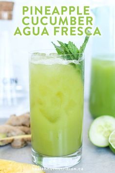 a glass filled with green liquid next to sliced cucumbers