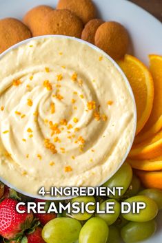 a white plate topped with oranges and grapes next to an appetizer dip