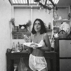 a woman standing in a kitchen holding a plate