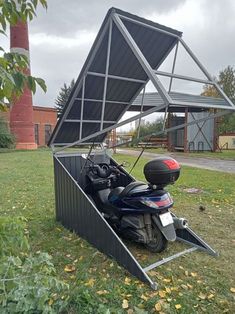 a motorcycle parked under a metal structure in the grass