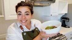 a woman is holding a bowl of food in her hands and smiling at the camera