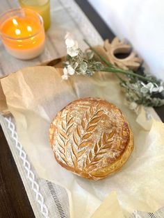 a pastry sitting on top of a piece of wax paper next to some candles and flowers