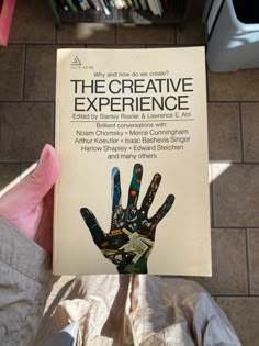 a person holding up a book about the creative experience