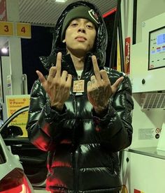 a man standing in front of a gas station giving the peace sign with his hands