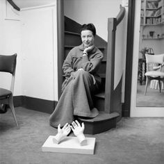 a black and white photo of a woman sitting on a chair with her feet up